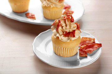 Tasty cupcake with bacon on plate