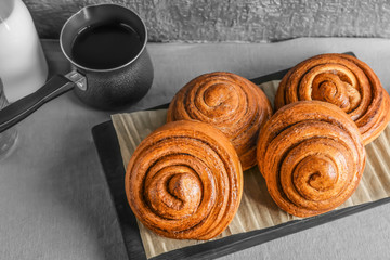 Wooden board with tasty cinnamon buns on table
