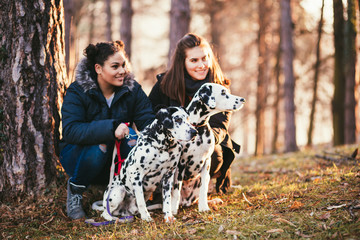 Young women with  their dalmatian dogs enjoying in park.