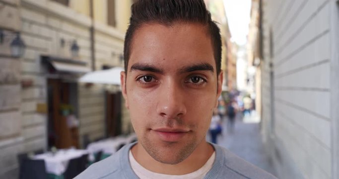 Wide angle closeup of attractive millennial guy on city street looking at camera