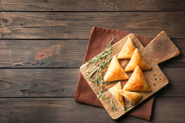 Wooden board with delicious meat samosas on table