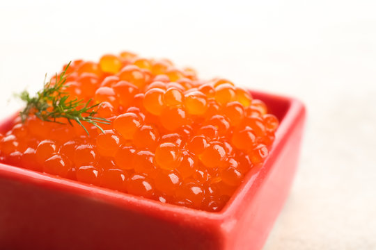Bowl with delicious red caviar on light background, closeup