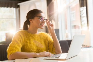 Young attractive and elegant female talking through video-chat while sitting in cafe