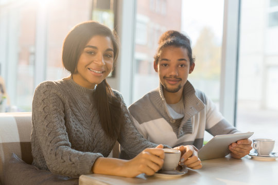 Young specialists in casualwear having tea or coffee in cafe during break