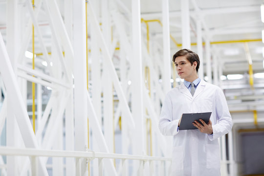 Young worker of mining farm with clipboard carrying out his work