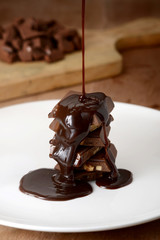 A stack of chocolate pieces and melted chocolate poured over it. 