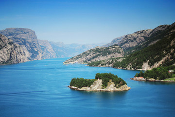 Fototapeta na wymiar Sunny blue Norwegian fjord mountains with an island