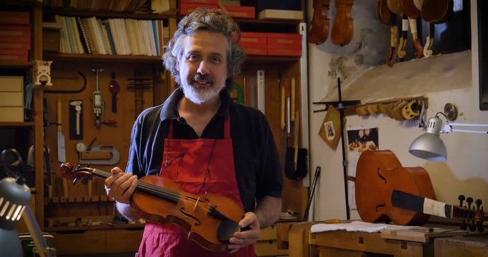 The professional violin master makes a violin with his own hands, uses a clean tree spruce, pine, glasses, planes, tunes strings. Concept: spiritual instrument, hand made, art, music, melody, sound.