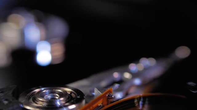 The hdd starts working, the head moves over the disk, the running symbols are reflected on its surface. Macro. Closeup. Shallow depth of field. Follow focus