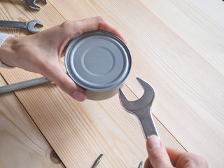 Funny opening tinned food. Funny geek girl trying to easy open a tin with a wrench and pliers.
