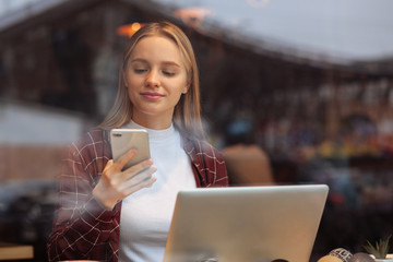 Positive delighted student looking at her telephone