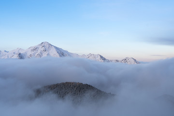 Mountains in winter emerge from the fog