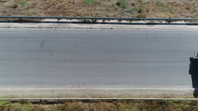 Aerial top-down view flight over road then garbage truck takes over other common names for this type of truck include trash truck rubbish truck waste collection vehicle and refuse collection vehicle