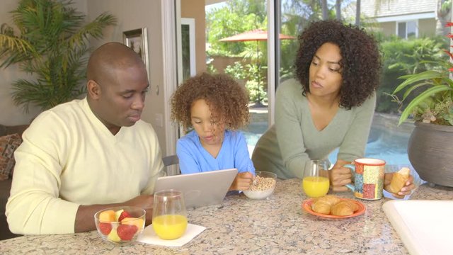 African American family  eating breakfast and using laptop