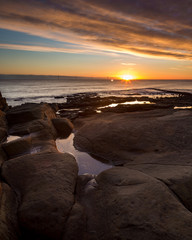 Dawn light reflecting in rock pools on rocks at Newbiggin By The Sea, Northumberland, England, UK.