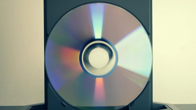 The hand puts the compact disk in the DVD player and after play get it back on white background. Top view. Closeup