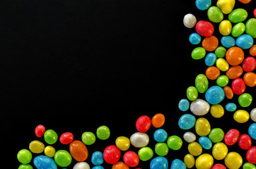 Multicolored candy on black background with space for text