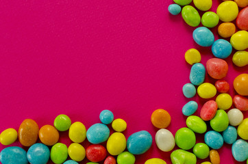 Obraz premium Multicolored candy on pink background with space for text