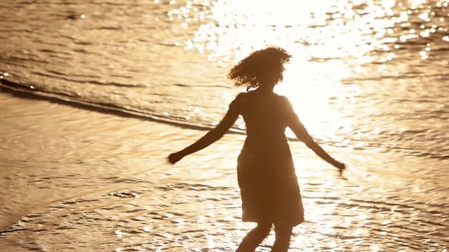 Silhouette of young woman dancing on beach