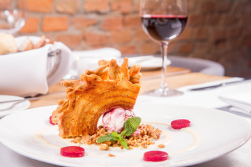 Polish-Lithuanian traditional spit cake ('tree cake') -sekacz (polish) or sakotis (lithuanian) with ice-cream, roasted nuts and raspberry jelly decorated wtih fresh mint served in a restaurant