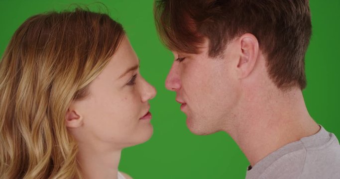 Close up of young Caucasian couple kissing on green screen. On green to be keyed or composited. 
