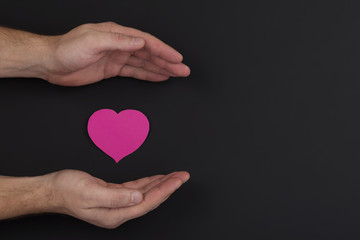 Obraz premium Heart in a palm on dark background with copy space