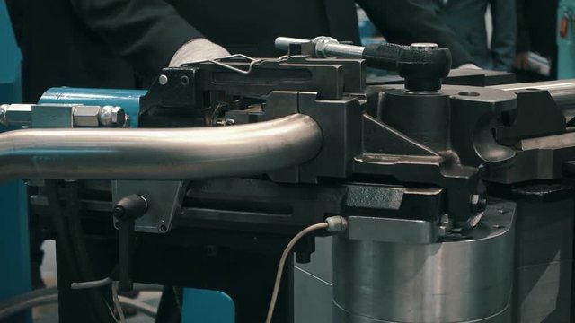 Industrial equipment for bending of metal pipes. The specialist shows the possibilities and telling the possibilities of machine