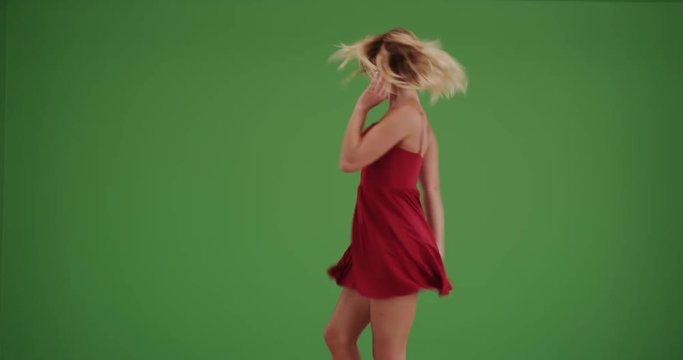 Happy woman dancing in a red dress on green screen. On green screen to be keyed or composited. 