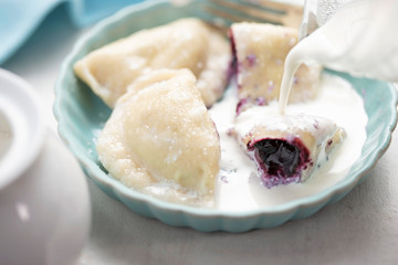 Dumplings with blueberries and cream. Sweet pierogi with berry fruit.