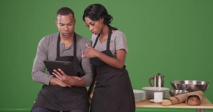 Small business owner showing employee new plan on tablet computer on green screen. On green screen to be keyed or composited. 