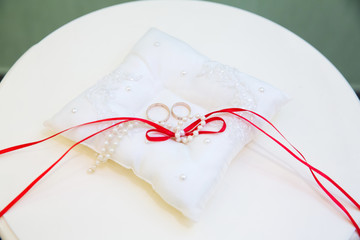 Naklejka premium Gold wedding rings on the pillow