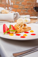 Apple pie with ice-cream decorated with a strawberry, fruit sauce and herb served in a restaurant
