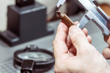A forensic service officer measures the cartridge case from a firearm with a caliper and conducts a...