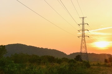Obraz premium View of High-Voltage Electric Transmission Tower in the Evening with Sunset Skies