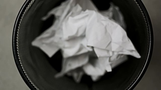 Stop motion animation of crumpled paper pieces dropped into trash can
