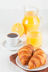 Freshly baked croissant, orange juice, fresh fruits, jam on white wooden background. French breakfast. Fresh pastries for morning. Delicious dessert. Closeup photography. Vertical banner