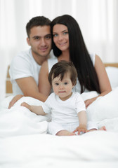 Fototapeta premium Portrait of a joyful family sitting on the bed at home