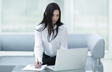 successful young woman sitting at a desk on a blurred background.