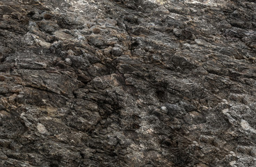 grunge background texture old stone wall potholes weathered, natural surface part of a dark mountain cliff