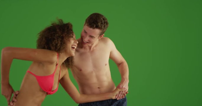 Couple of young adults playing in beach water on green screen. On green screen to be keyed or composited. 