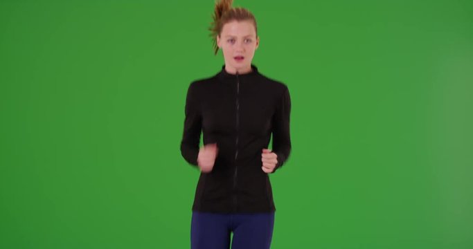 Young white girl in sportswear running toward the camera on green screen. On green screen to be keyed or composited. 