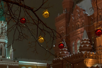 Christmas decoration celebrating  New year in Moscow, golden and red balloon on  branch, on  background of the building of the historical museum and the Kremlin tower