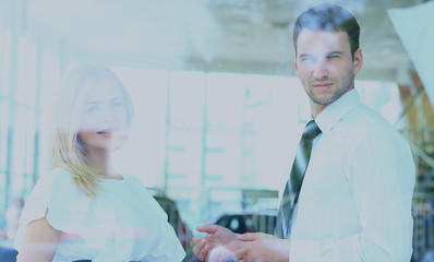 Obraz premium Two cheerful smiling young businesspeople talking at the office. View through window