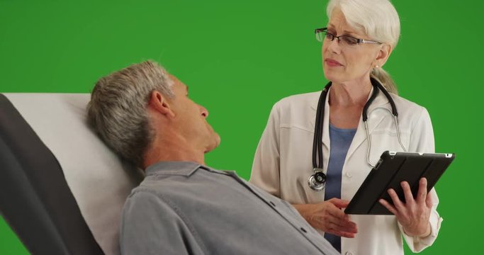 Senior man patient talking with doctor about his health concerns on green screen. On green screen to be keyed or composited. 