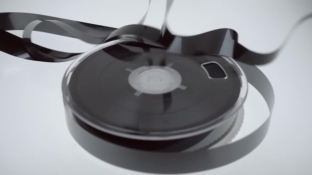 On the coil VHS the magnetic tape falls on it in large quantities on white background. Closeup. Slow mo, slo mo, slow motion, high speed camera, 240fps, 250fps