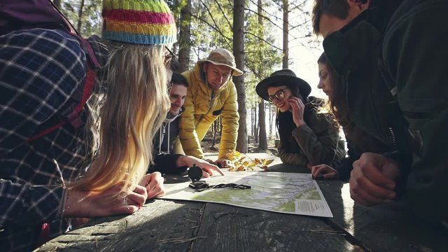 Group of friends discussing over map in forest