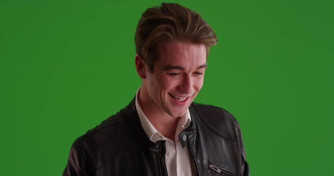 Portrait of Caucasian male in leather jacket winking at camera in evening on green screen. On green to be keyed or composited. 
