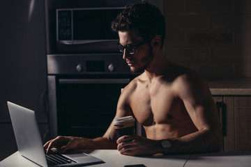 Physically Fit Man Using Laptop and drink coffee at morning - obrazy, fototapety, plakaty