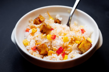 vegetarian rice salad with tofu and brown rice on black background.