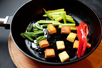 Vegetables in a frying pan are fried. Black background